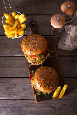 Klasik Amerikan usulü sığır burger, ızgara köfte üzerine erimiş peynir, domates, soğan, sos ve patates. Yukarıdan görüntüle, en üstten