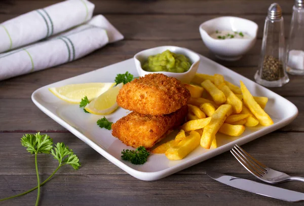 Fish and chips served with lemon, mushy peas and sauce. Battered fish with french fries