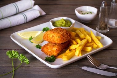 Balık ve patates kızartması, bezelye püresi ve beyaz tabakta sos. Yatay resim