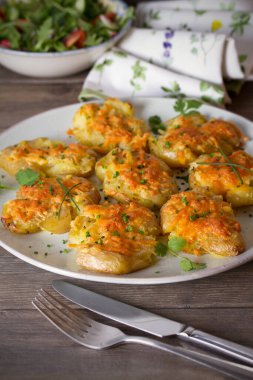 Tahta arka planda sarımsaklı tereyağlı ve peynirli yeni bebek patatesleri ezdim. Temiz yemek.