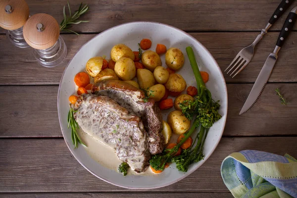 Biftek fileto, kremalı Gorgonzola peyniri sosu ve tabakta sebze. Tepede düz bir resim var.