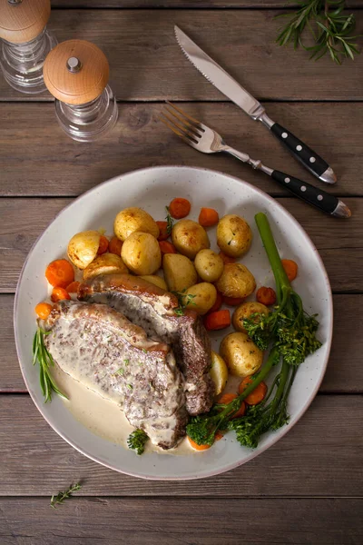 Biftek fileto, kremalı Gorgonzola peyniri sosu ve tabakta sebze. Tepede düz bir resim var.