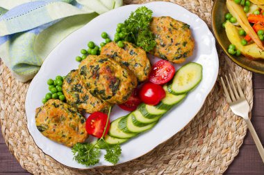 Beyaz tabakta yeşil bezelye ve sebzeli tavuk ıspanaklı burger. Yukarıdan bak, en iyi stüdyo çekimi.