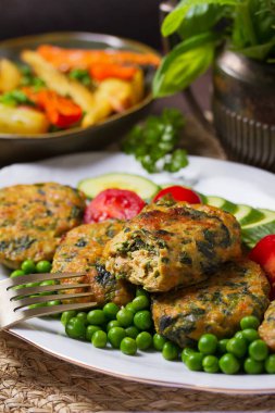 Beyaz tabakta yeşil bezelye ve sebzeli tavuk ıspanaklı burger.