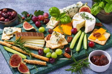 Çeşitli peynir çeşitleri var. Peynir seçimi. Üzüm, incir, fındık ve turşuyla servis edilen peynir tabağı. Şarap bardakları. Şarap için yiyecek.