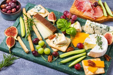 Çeşitli peynir çeşitleri var. Peynir seçimi. Üzüm, incir, fındık ve turşuyla servis edilen peynir tabağı. Şarap bardakları. Şarap için yiyecek.