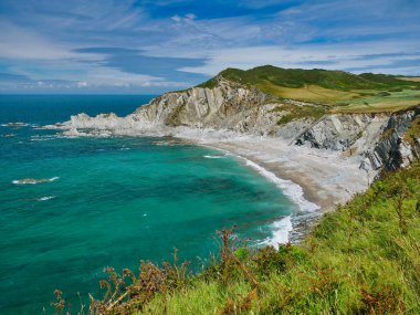 Rockham Sahili 'nin kuzey Devon kıyısı, Devonian Dönemi' nde oluşmuş olan Morte Slates Formasyonu 'nun dik eğimli kayalık tabakasını gösteriyor. Güney batı yakası patikasından alındı..