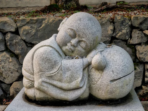 A sculpture of a sleeping figure, perhaps a monk, with donated money at Mount Koya (Koya-san), the temple complex in Wakayama Prefecture to the south of Osaka, Japan