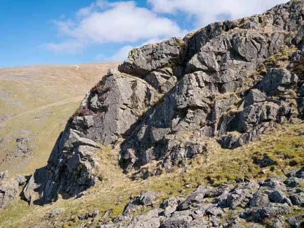 Against a blue sky, an igneous rock outcrop near Comb Crags, Birk Side, near Helvellyn in the Lake District National Park, Cumbria, England, UK.