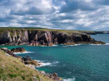 Galler 'deki St David' s yakınlarındaki Pembrokeshire Sahil Yolu 'ndaki St Non' s Bay 'de Kambriyen Dönemi' nden kalma kırmızı kumtaşı tortusu kayalıkları.