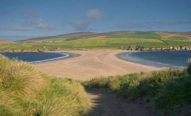 The sand spit, or tombolo, that joins St Ninian's Isle to Mainland Shetland - taken from the island looking across to the farmland of south Mainland. clipart