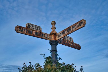 Wirral, İngiltere 'de Gayton, Heswall, Thornton Hough ve Birkenhead' e yol gösteren eski paslı bir tabela.
