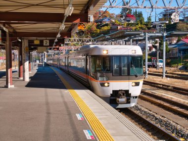 Modern, yerel, elektrikli bir banliyö treni kasım ayının güneşli bir sabahında Kiso Fukushima İstasyonu 'ndaki boş bir platforma ulaşır..