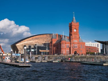 Sonbaharda güneşli bir günde Cardiff, Galler 'deki Cardiff Körfezi' nde Galler Milenyum Merkezi 'nin bakır çatısı ve Pierhead Binası' nın kırmızı tuğlası görülebilir..