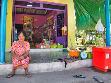 Sahibi, Kamboçya 'nın Koh Kong eyaletindeki ücra bir kırsal köyde küçük dükkanının önünde oturuyor..