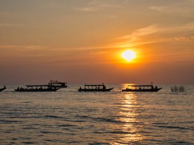 Turistler, Kamboçya 'daki Siem Reap yakınlarındaki Tonle Sap Gölü' nde gün batımının keyfini çıkarıyorlar..