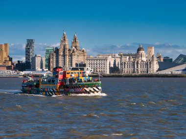 Mersey Nehri Feribot Kar Damlası güneşli bir öğleden sonra tarihi Liverpool rıhtımında Three Graces 'i geçer. Feribot göz kamaştırıcı bir gemi stiliyle süslenmiştir. Sör Peter Blake 'in 
