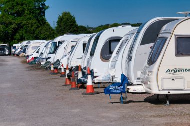 Yazın güneşli bir günde mavi gökyüzü olan güvenli bir karavan deposunda zorlu bir yolculukta olan bir grup beyaz karavan..