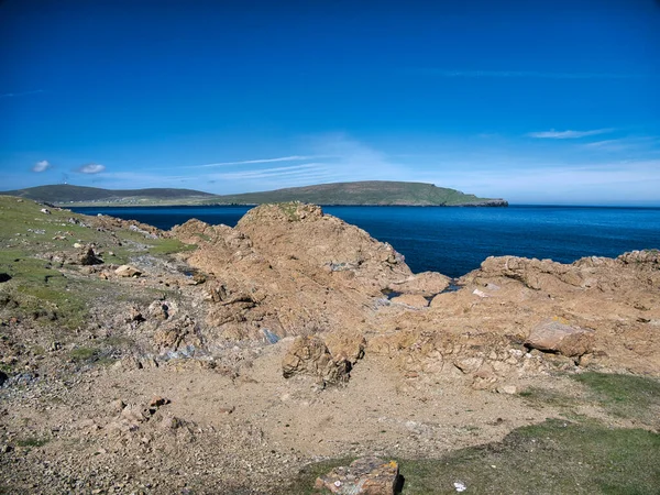Coastal serpentine rock at the Keen of Hamar Nature Reserve near Baltasound on the island of Unst in Shetland, UK. The white  dome of the RAF Saxa Vord remote radar head can be seen in the distance.