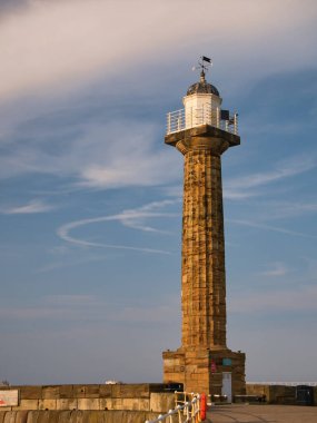 İkinci derece, İngiltere 'nin kuzeyindeki Whitby, North Yorkshire' daki East Pier Deniz Feneri 'nin tarihi kumtaşı kulesi yaz sonlarında sakin ve güneşli bir günün sonunda çekilmiştir.