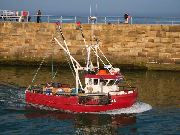 イギリスのノースヨークシャーの東海岸にあるウィットビー港に赤い漁船が戻り 夏の終わりの午後に撮影されました — ストック写真