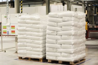 Tüketilebilir plastik malzemeler depolamak için bir depodaki palet tezgahına eşit ve düzgünce katlanmış beyaz torbalar.
