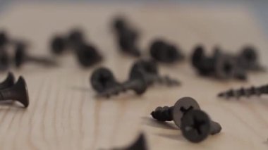 Siyah demir vidalar ahşap bir masaya düşer ve yavaş çekimde zıplar. homojen arka plan. 180 fps