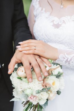 Sevgililer sıcak bir yaz gününde gün ışığında el ele tutuşurlar. Düğün yürüyüşünde. Damat parmaklarıyla düğün buketine dokunur.