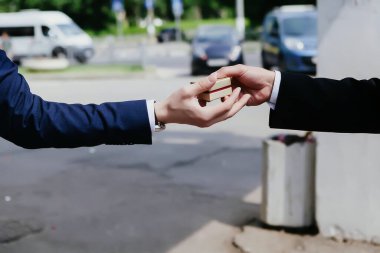 Siyah takım elbiseli bir el hediye kutusunu diğer ele uzatıyor..