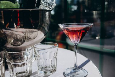 Masadaki diğer bardakların yanında kırmızı şarapla dolu beyaz masa örtüsü olan bir bardak duruyor. metin eklenecek bir yer var