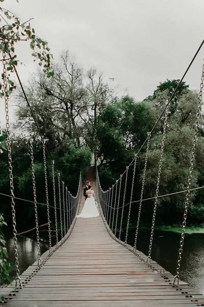 Bröllopsparet Står Omfamnande Bro Över Flod Bron Går Fjärran Till — Stockfoto