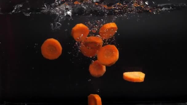 Muchas Rodajas Zanahorias Frescas Caen Agua Con Aerosol Hundiéndose Lentamente — Vídeo de stock