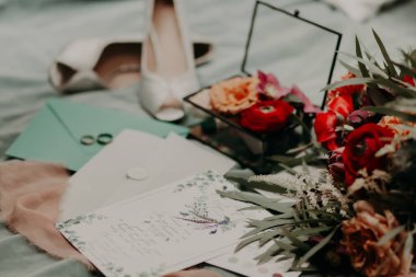 Alyanslar bir zarfın üzerinde davetiye mektupları, kıyafet kuralları notları ve çiçeklerle dolu bir kutu var..