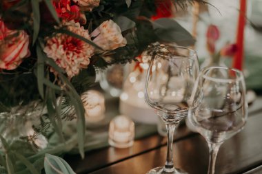 Büyük bir buket, fenerler ve mumlarla süslenmiş yeşil ve kırmızı renklerde bir düğün masasının dekoru..