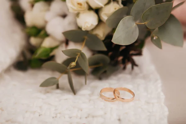 在一束由白玫瑰和其它紫色花朵组成的美丽的婚礼花束旁边 金戒指相映成趣 — 图库照片