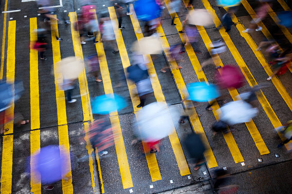Motion blurred pedestrians crossing Hong Kong street in the rain