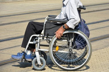 Sokakta tekerlekli sandalyedeki yaşlı adam.