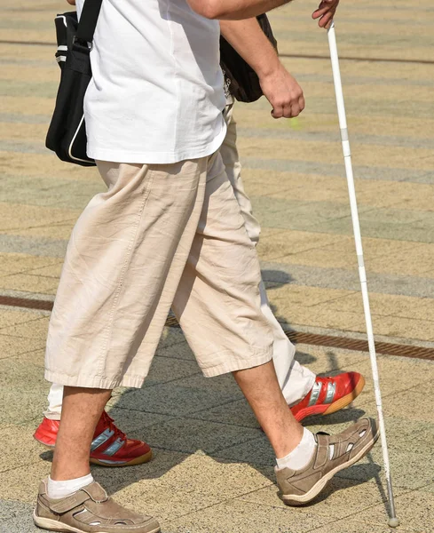 Blind man walks with a white cane