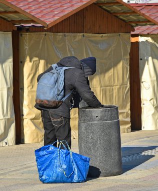 Evsiz bir adam sokakta çöp yiyecek arar