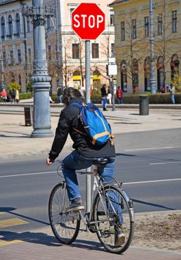 Şehirdeki stop tabelası ile bisiklet olan adam
