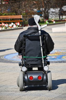 Yaşlı adam sokakta bir elektrikli tekerlekli sandalyede