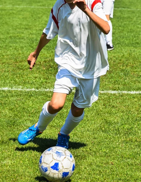 Un jeune footballeur court avec un ballon — Photo