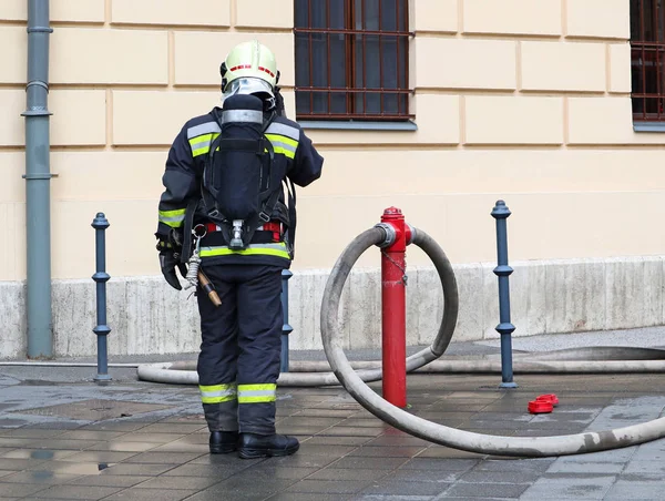 Firefighter at work with hose and oxygen tank — Stock Photo, Image