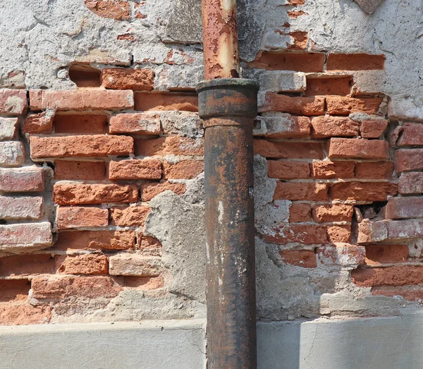 Vecchio muro di mattoni in rovina con grondaia — Foto Stock