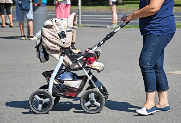 Mulher com uma carruagem de bebê na rua — Fotografia de Stock