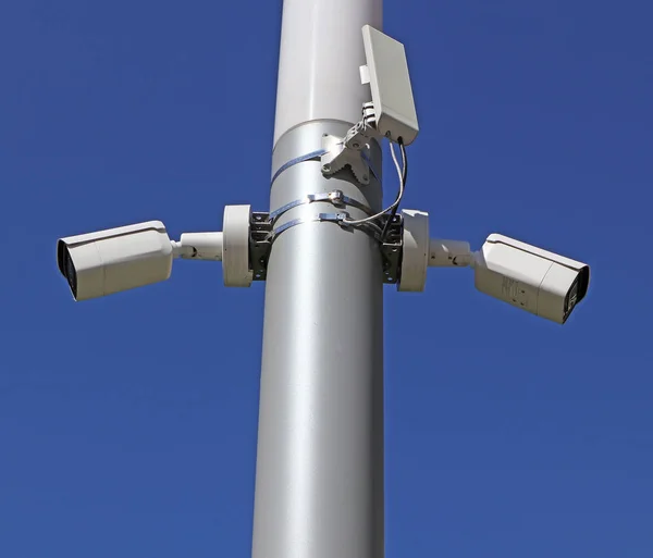 Security cameras and a wifi router on a metal pole outdoors