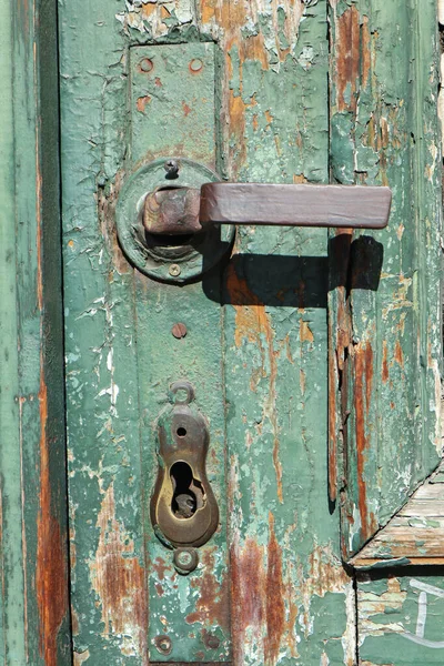 Maçaneta da porta de uma porta de madeira verde — Fotografia de Stock