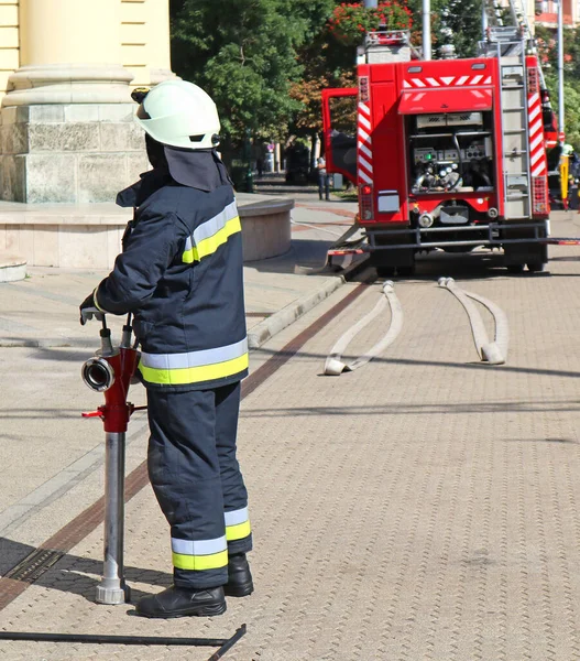 Firefighter and a firetruck on the street — Stock Photo, Image