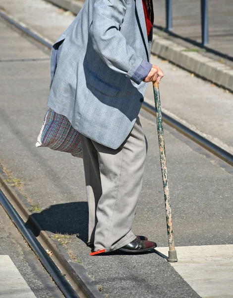老人带着手杖走在城市街道上 — 图库照片