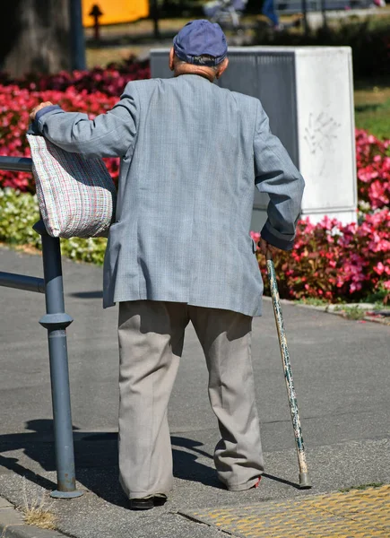 老人は街の通りを棒で歩く — ストック写真